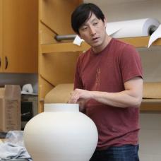 Man stands behind a ceramic vase