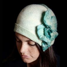 Wet felted Merino wool cloche in creme and pale green with a set of large Caladium leaves cascading down the left side.