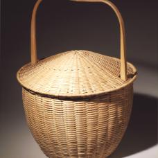 Captured lid basket. Woven of pounded brown ash splint with hand split carved and green bent brown ash rims and handles.