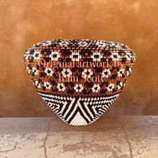 Vessel is created with metallic paper with the shape of an infinity rim pot. The floral design is an old style Acoma design  popularized in the 40’s and 50’s. The black and white portion at the bottom is inspired by Pima basket weavings of water wave designs. The overall design represents the flowers and vegetation that grows by rivers and streams but an alternative meaning is the flowers flowing into the infinity rim represent prayers of abundance and prosperity that goes with this pot to its new home