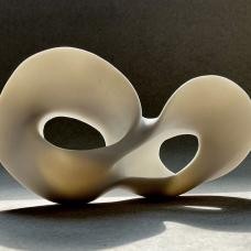 This high fired porcelain piece was created by pinching  carving  and handbuilding. It has an unglazed surface.