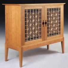 Shaker and Japanese inspired solid cherry cabinet featuring the asa-no-ha (hemp leaf) kumiko pattern backed by black crinkled Japanese momigami paper in the doors. The door pulls are ebonized cherry. The interior features a solid wood adjustable shelf. The back is frame and panel construction.