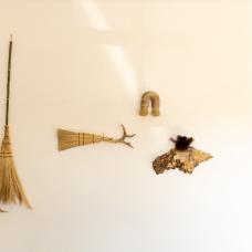 A still from an installation in 2022 including full sweepers on the left  cobweb brooms on the right and three sculptural pieces at center