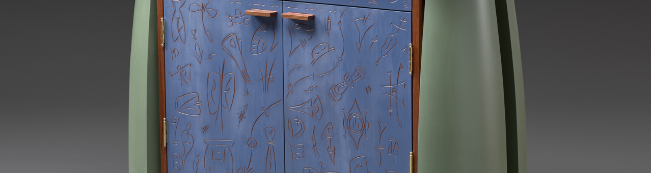 A green cabinet with blue doors and carved in designs on the doors