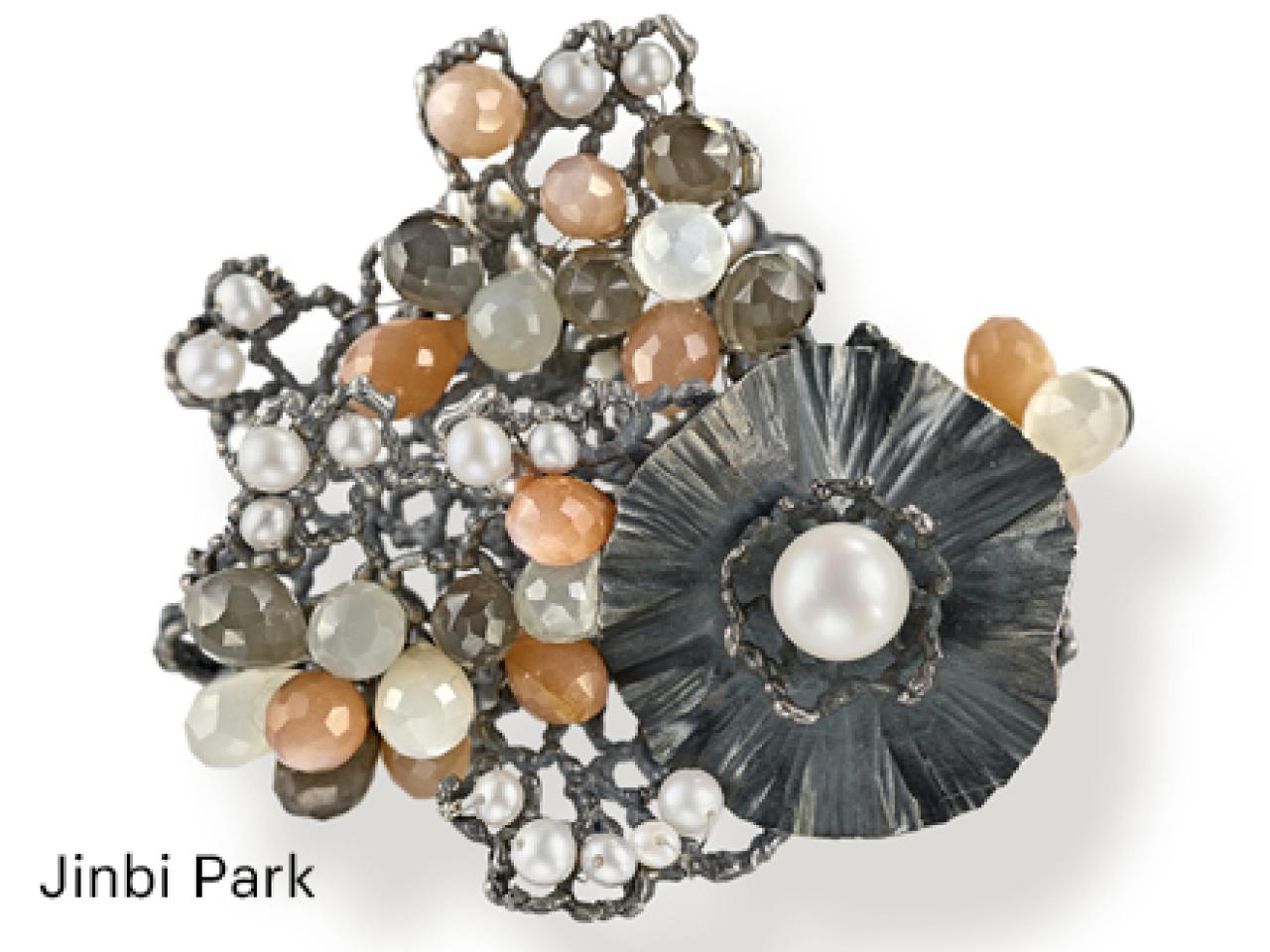 broach with many different colored pearls on a matt metal backing